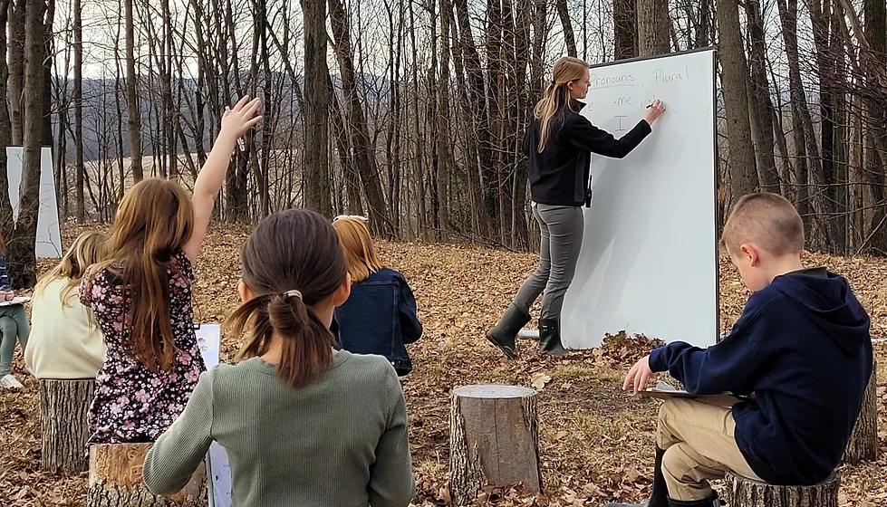 teacher writing on white board in outdoor classroom