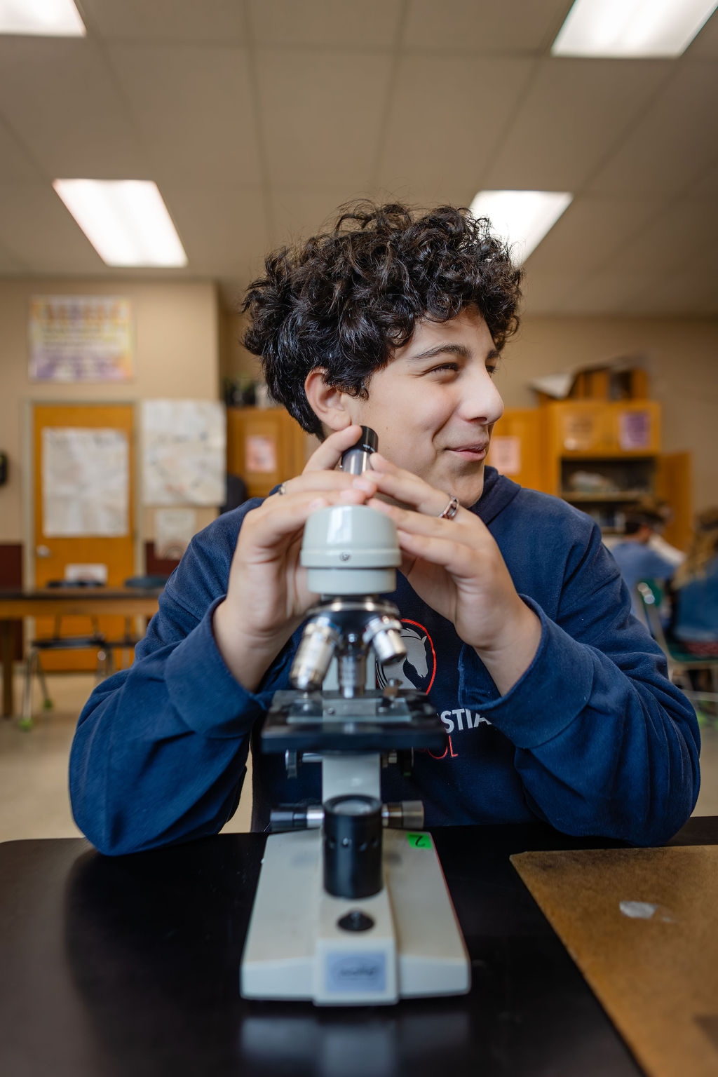 middle school boy looking in microscope