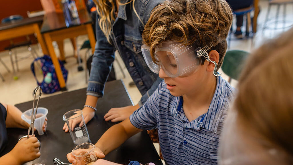 middle school student with goggles in science class
